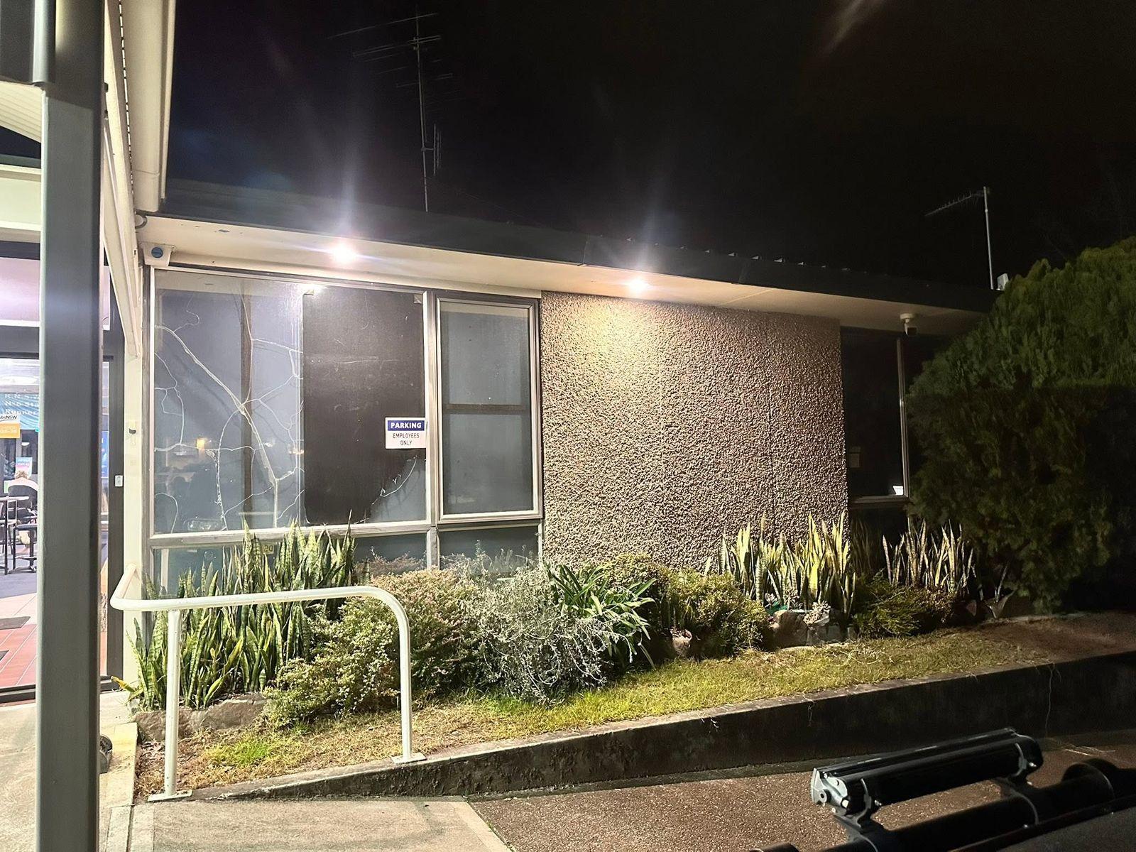 Security lights lighting the front of a brick building and garden at night