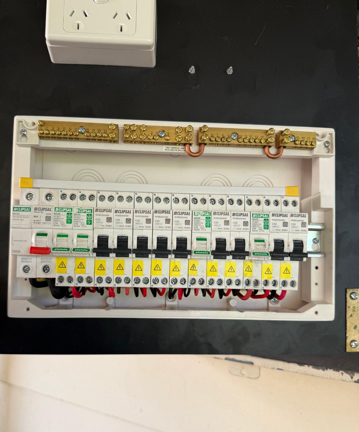 New Clipsal switchboard with a main switch and a combined safety switch and breaker on every circuit, with a double power point above